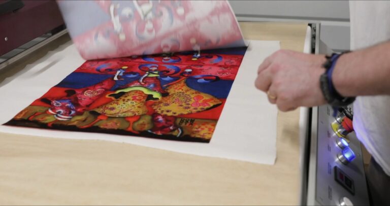 Papier de transfert décollé révélant un motif coloré imprimé sur tissu, atelier Up'Textile